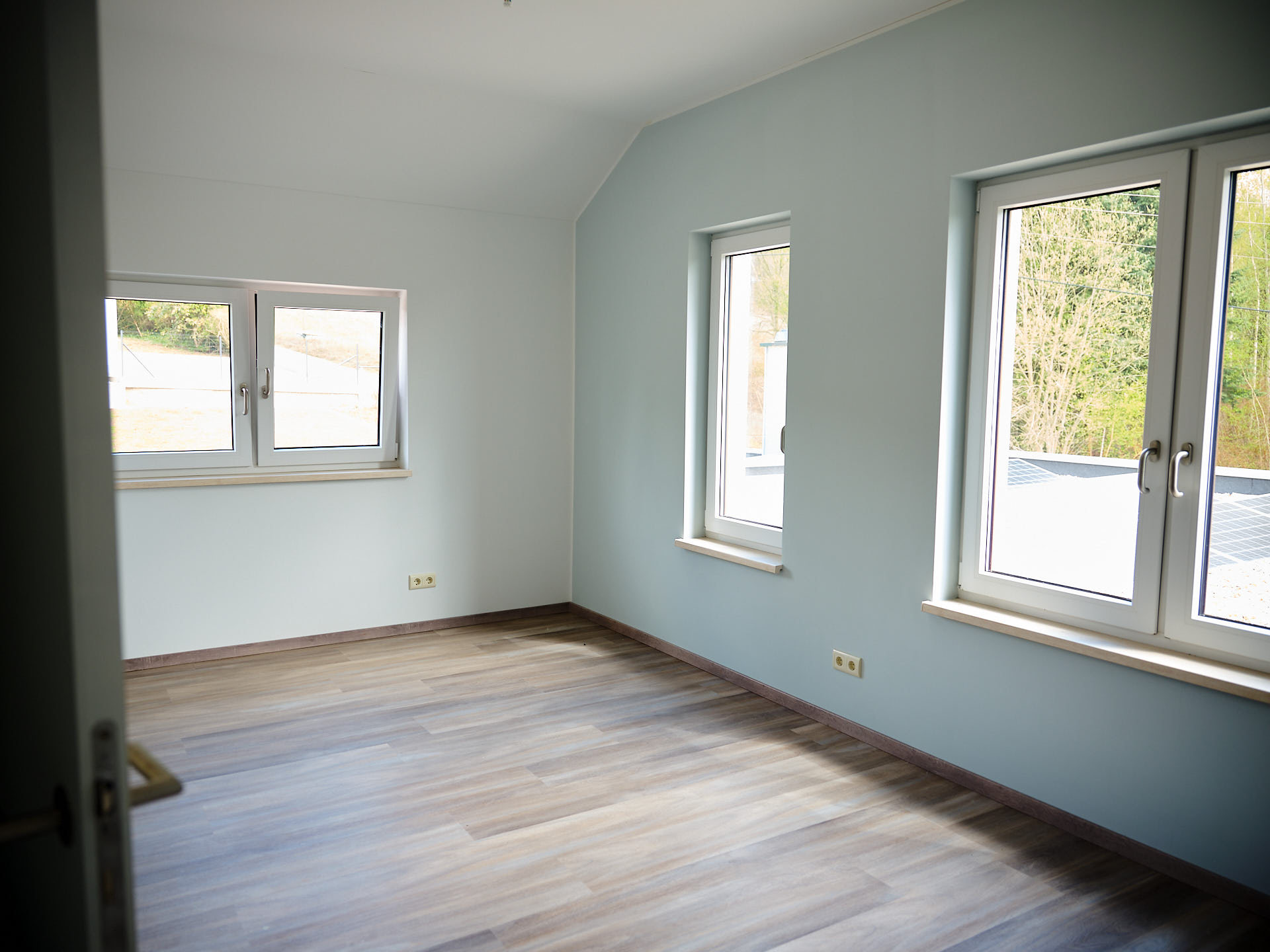 Modernes Zimmer mit blauer Akzentwand, natürlichem Licht durch zwei Fenster und zeitlosem Fußboden-Design.